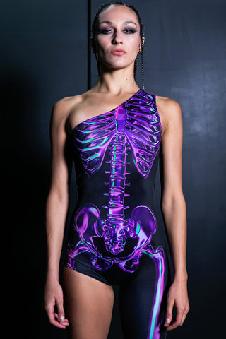 Woman wearing Halloween jumpsuit with one leg and one shoulder with purple skeleton print