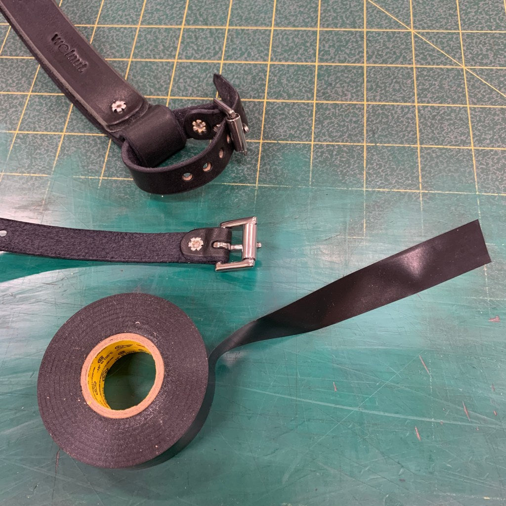 Cutting a piece of electrical tape to protect bicycle paint job from accessory rivets on Bicycle Frame Handle: one piece of tape cut lengthwise: shown with standard electrical tape roll in black