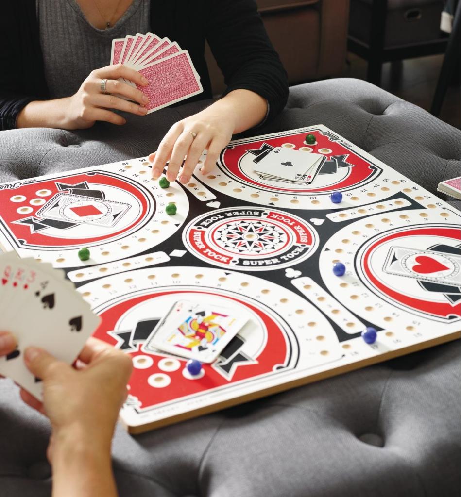 Four people playing Tock Canadian pachisi board game with playing cards