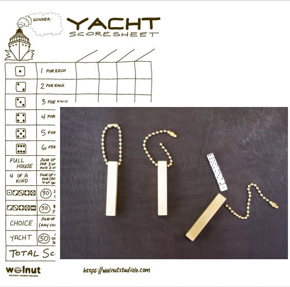 A hand-drawn Yacht score sheet for playing dice like Yahtzee but a little different, shown with a set of handcrafted travel dice that stay secured in a brass keychain