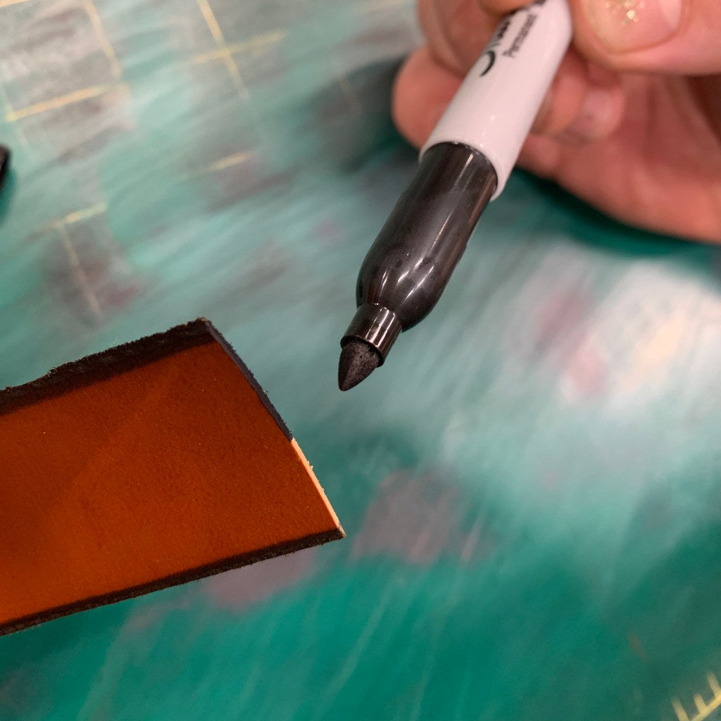 Leathercrafter using a sharpie marker as a DIY edge dye on a cut leather edge