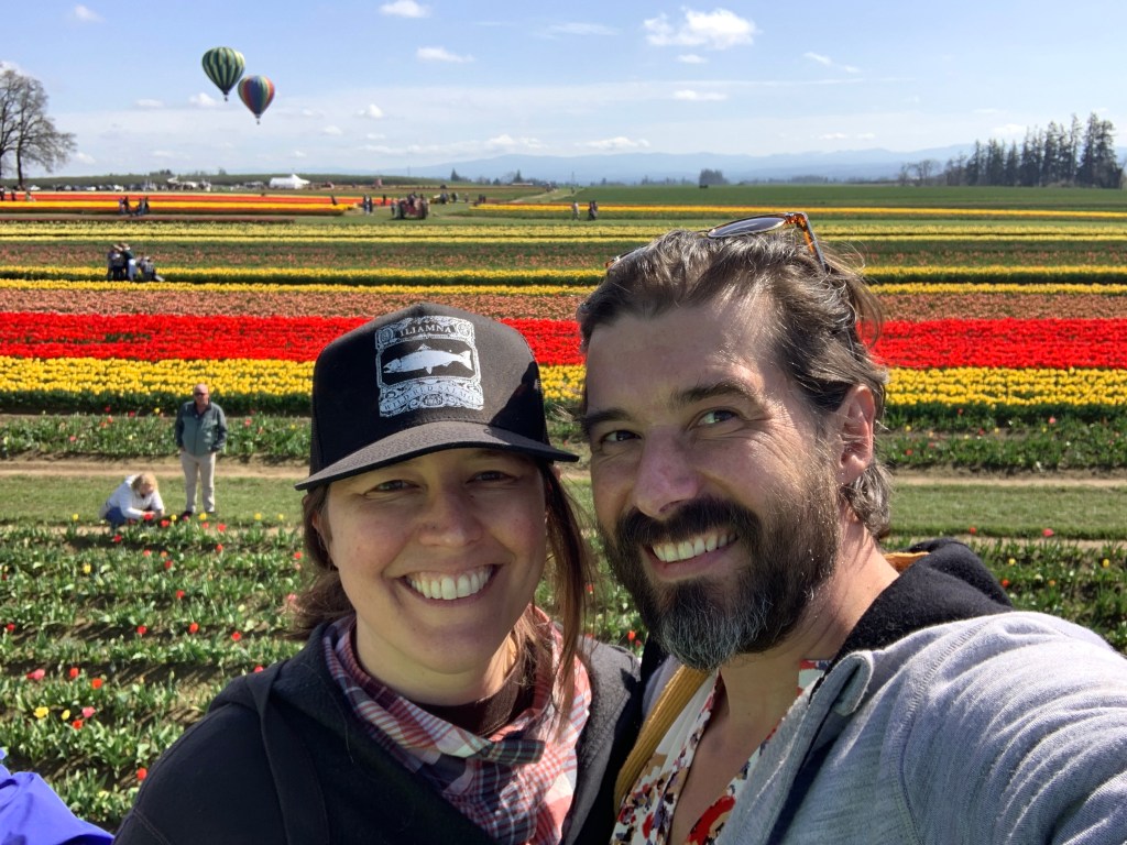 Valerie Schafer Franklin and Geoffrey Franklin Standing in Front of a Field of Tulips and Hot Air Balloons at Oregon Tulip Fest at the Wooden Shoe