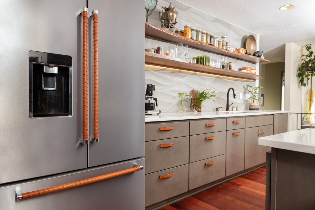 Muted neutral kitchen with warm honey leather wrapped refrigerator handles and leather drawer pulls and cabinet handles