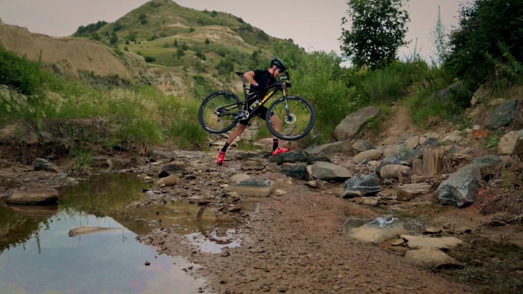 Mountain Biker Kelly Magelky crossing a stream in the North Dakota Badlands