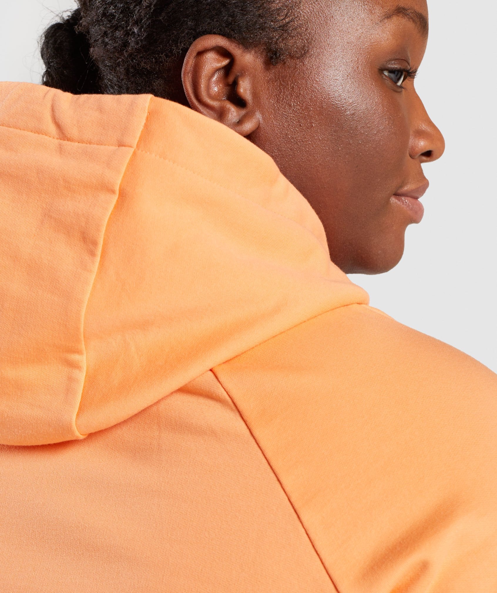 Image D2 shows a close up of back of model wearing Training Hoodie in Orange