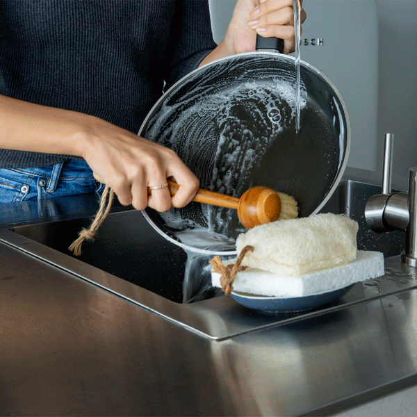 Using a Sqwishful bamboo dish brush to wash a pan