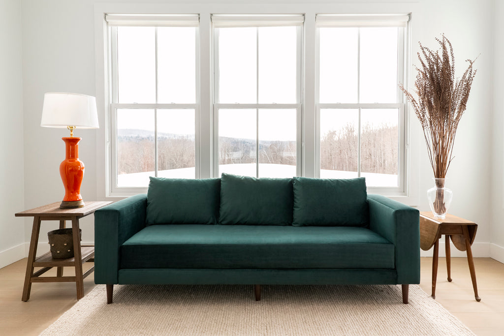Green Sabai sofa made from sustainable materials in front of a large window