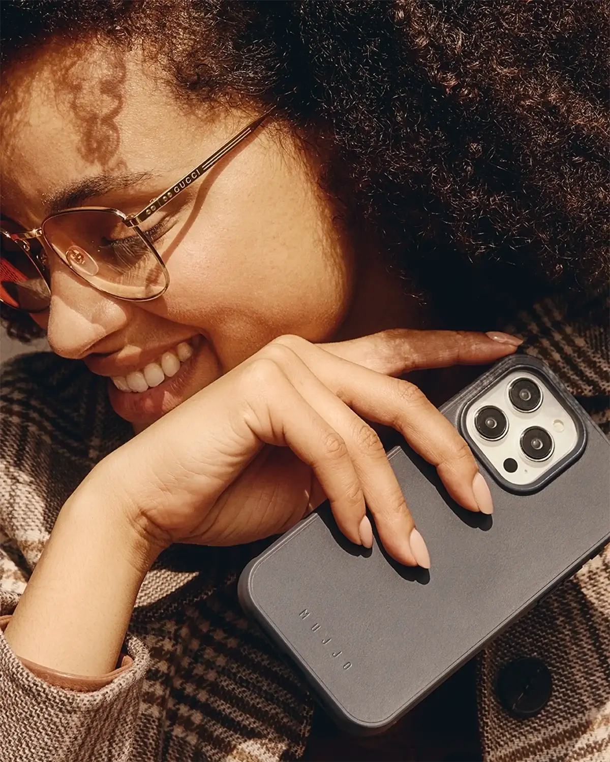 A woman featured holding Mujjo's iPhone Case 15 in Black