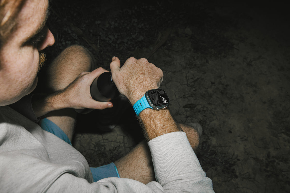 A man sitting with a Nomad's Watch Band in Electric Blue on his wrist