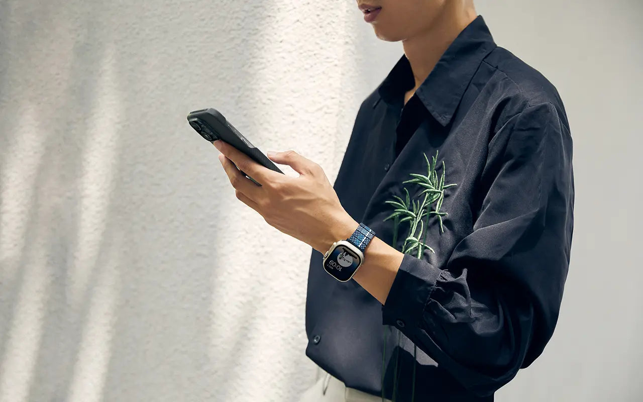 A man holding a phone in his hands featuring PITAKA's watch band in MOON.