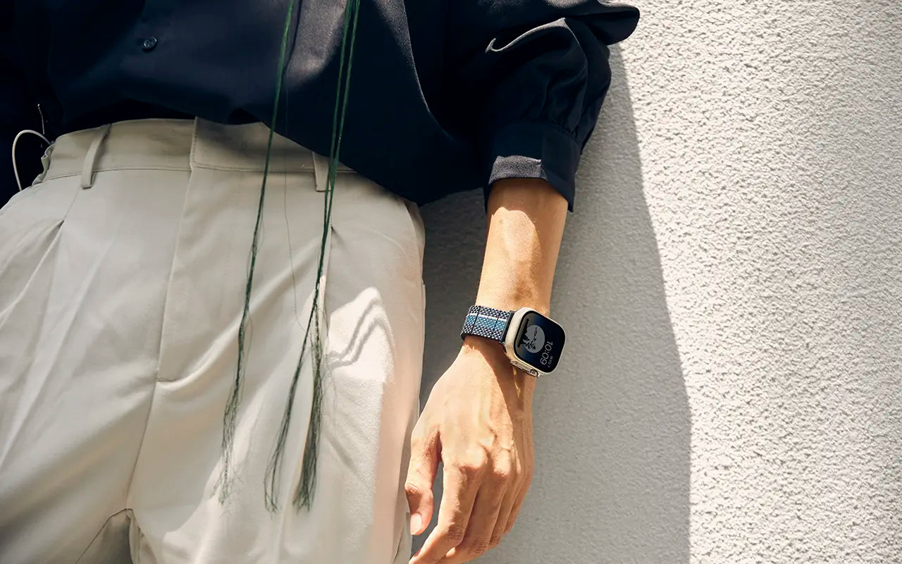 A man standing against the wall featured with PITAKA's watch band on his wrist