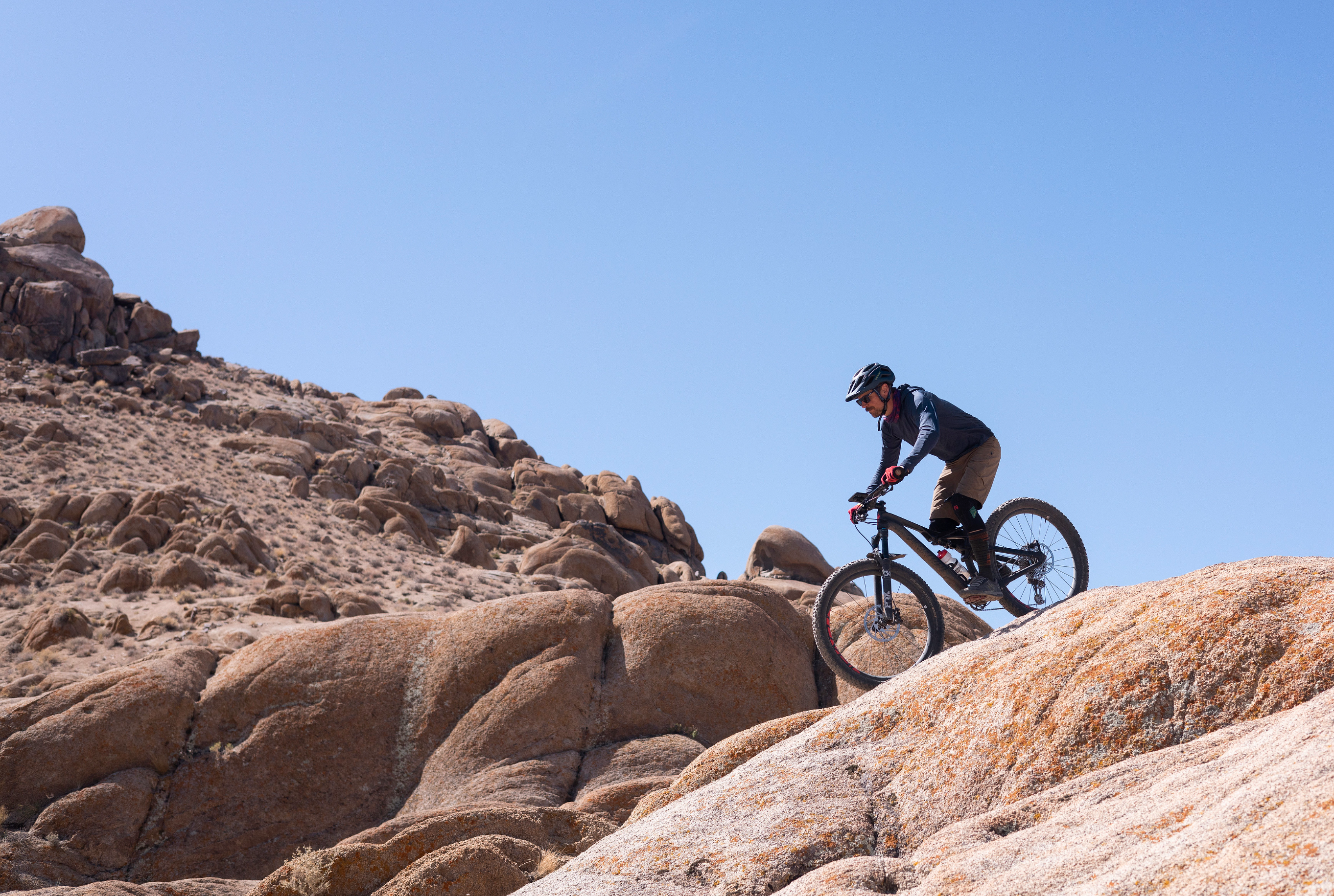 A photo of a man riding a bike in a dessert and featuring the Peak Design's Bike Mount on it