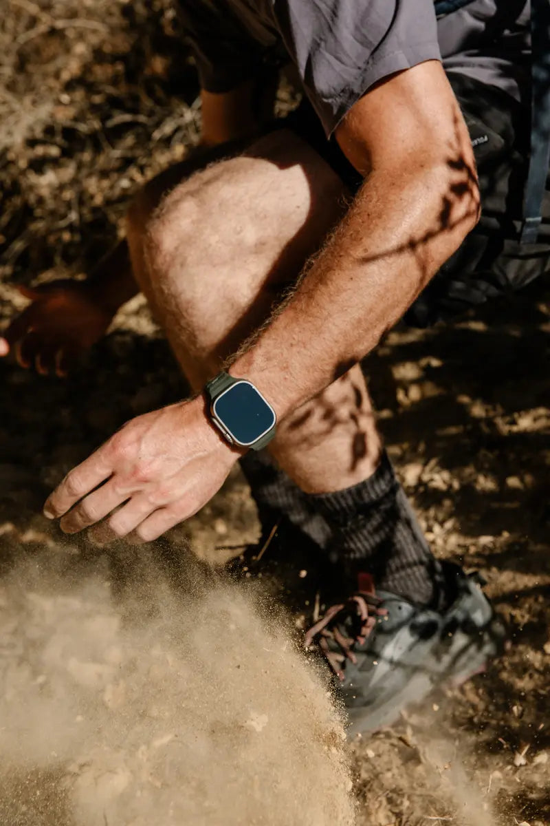 A man captured sitting on the grass with his Apple Watch on his wrist