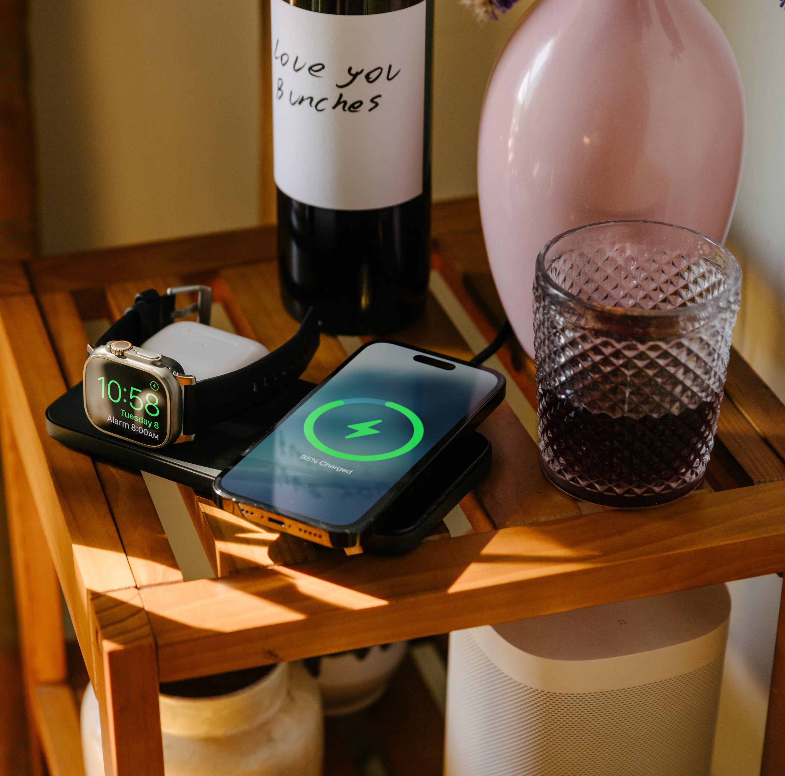 Nomad Base One Max charger in colour carbide on the bedside table charging an iPhone, Apple Watch and AirPods