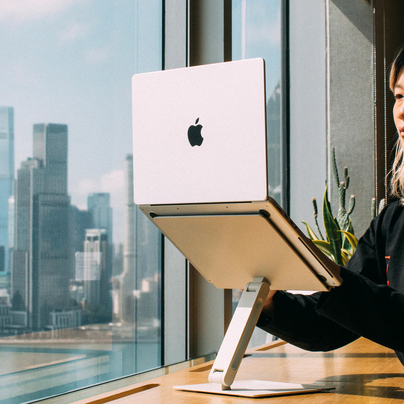 A Native Union Desk Laptop Stand in Sandstone with a MacBook on it and woman working