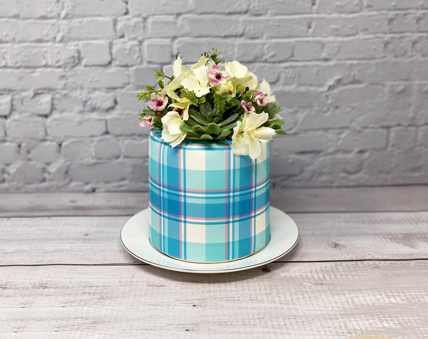 Aqua and pink icing cake wrap with a floral arrangement on top