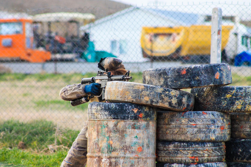 image of a person hiding behind a tire barrier while holding a paintball gun