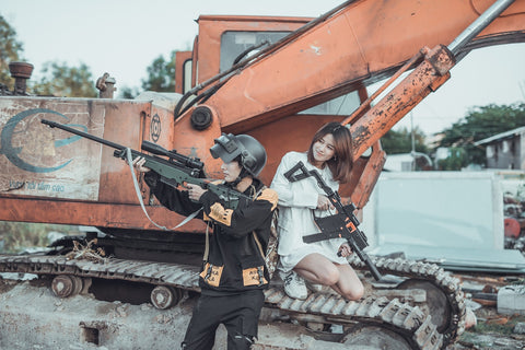 Image of a young man and a woman with gel blasters near to an excavator