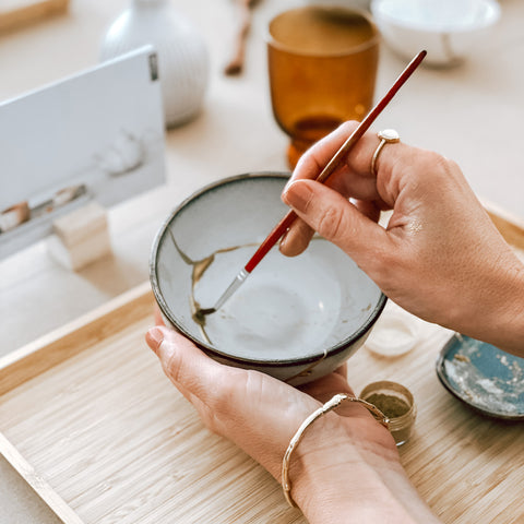 A close up of a woman mending a ceramic bowl using Kintsugi during a byFoke Kintsugi workshop in Poundbury