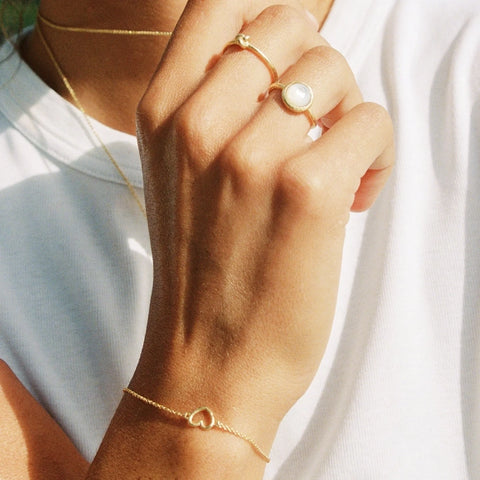 A close up of a woman's hand wearing the Paulina Gold Knot Ring by Agape Studio