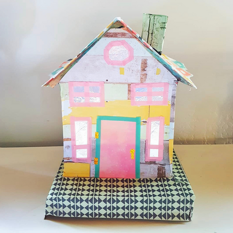 A colorful miniature house made of paper. The paper is fun prints and colors such as pink, green, and metallics.