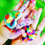 two hands covered in paint holding painted hearts