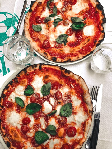 Two wood-fired pizzas, with cheese, basil, tomatoes, and mozzarella