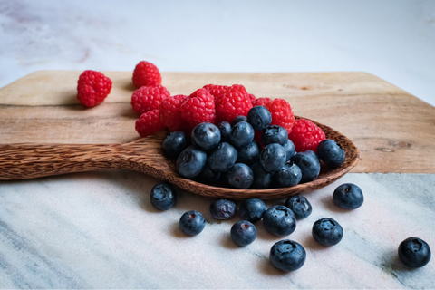 Raspberries and blueberries on a wooden spoon
