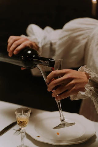 A person pouring a glass of red wine