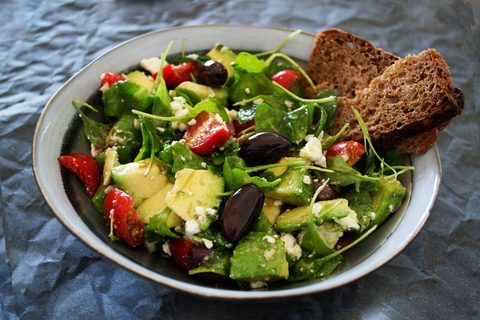 A green salad with tomatoes, avocados, and olives