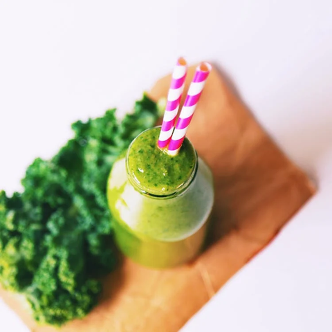 A green smoothie, with a pink and white straw