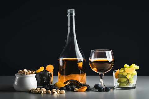 A bottle of non-alcoholic rose, pistachios, apricots, and grapes