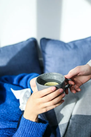 A person holding a ceramic gray mug of hot tea