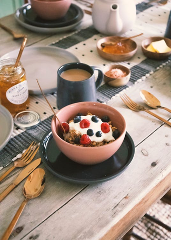 A bowl of fruit and yoga, with a cup of coffee