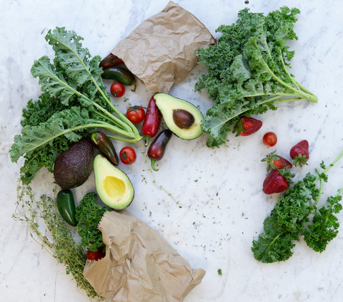 A display of kale, avocados, jalapenos, tomatoes, and strawberries