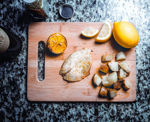 A cutting board with fish and lemon