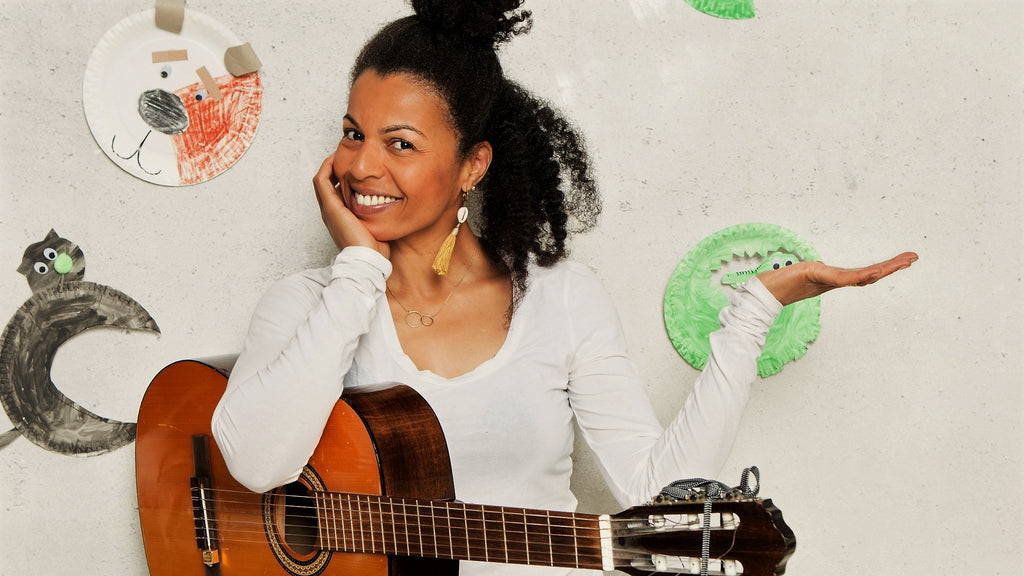 Frau mit Gitarre vor Wand mit gebastelten Tieren aus Papptellern