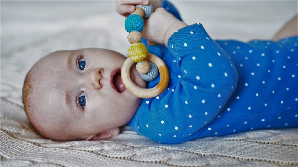 Baby mit blauen Augen spielt mit Rassel