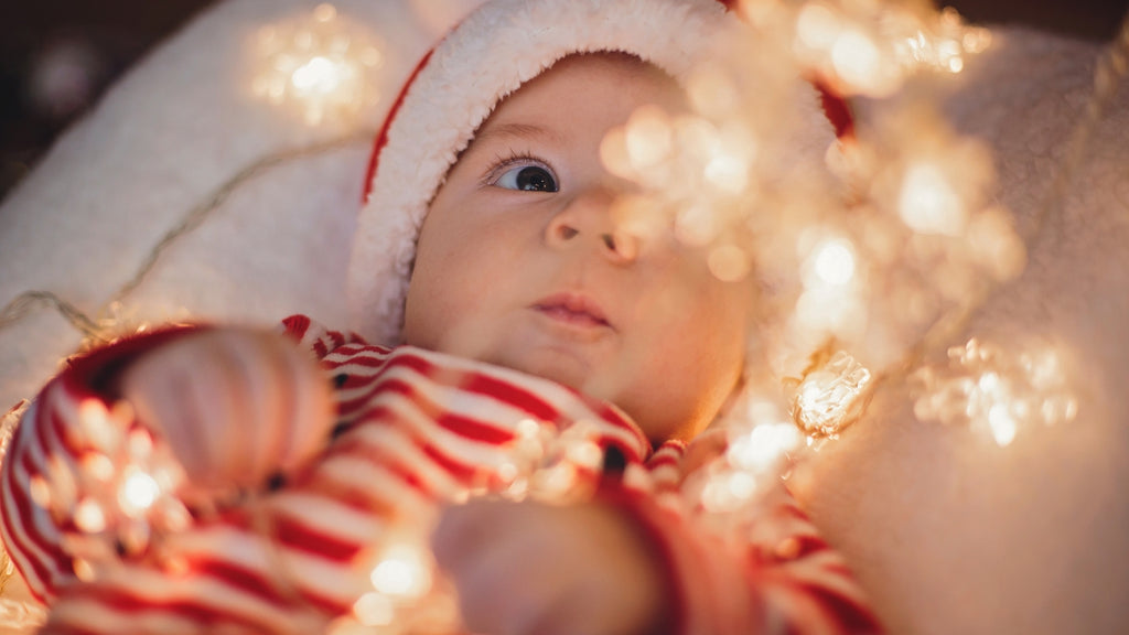 Baby mit Weihnachtsmütze und Lichterkette