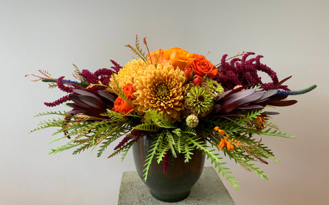 Autumnal flowers in a dark green container