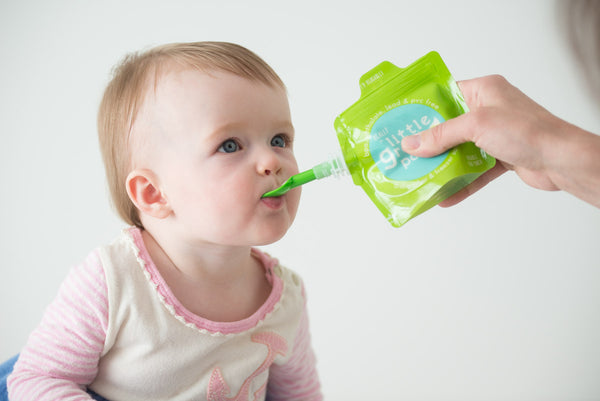 Baby girl Parker enjoys a no-mess pureed snack from a Really Little Green Pouch fitted with a reusable dispensing spoon