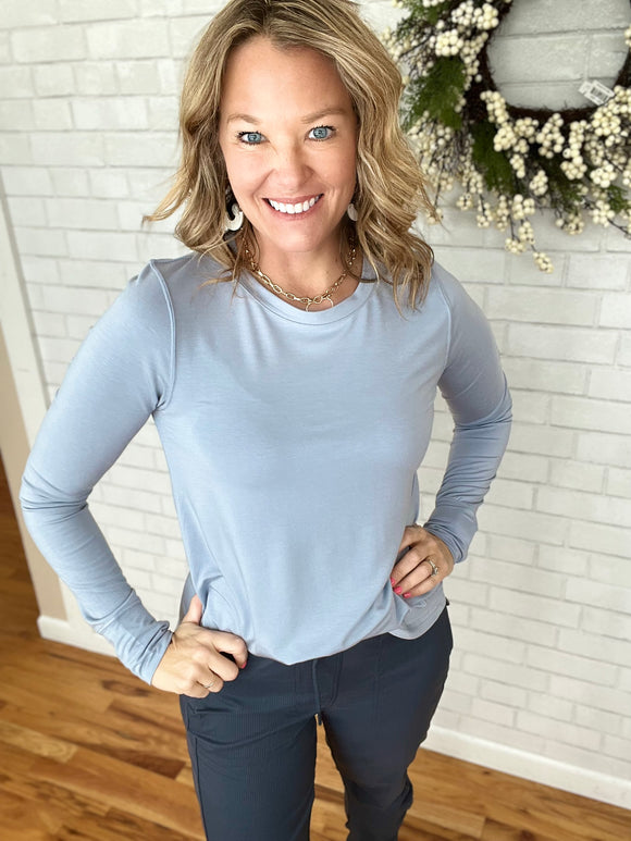 A gorgeous silky, long sleeve basic layer. Features a crewneck, slight high low and thumb holes. Christy is wearing a small.   95% Tencel   5% Spandex 