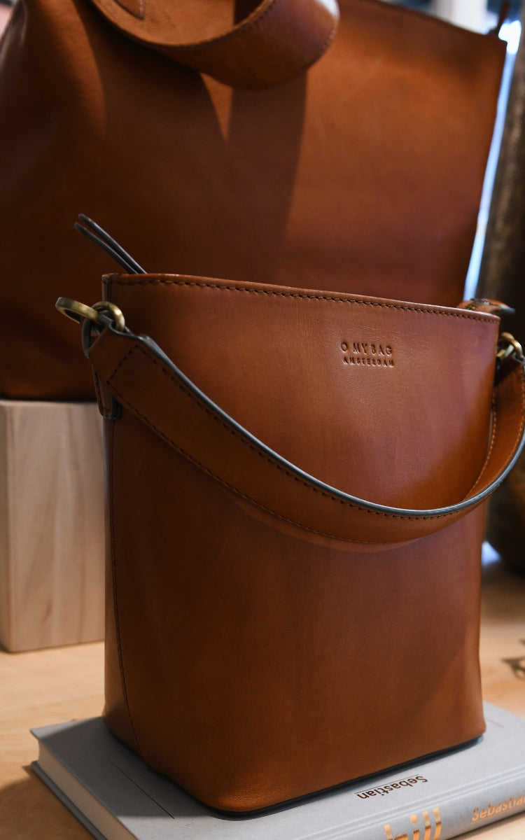 Elegant brown leather bag on a book with blurred background.