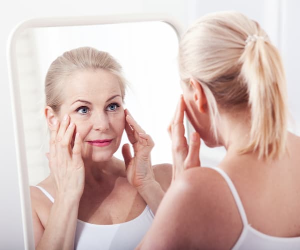 Woman looking at wrinkles in the mirror