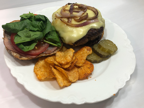 buffalo burger on a white plate with chips and pickles