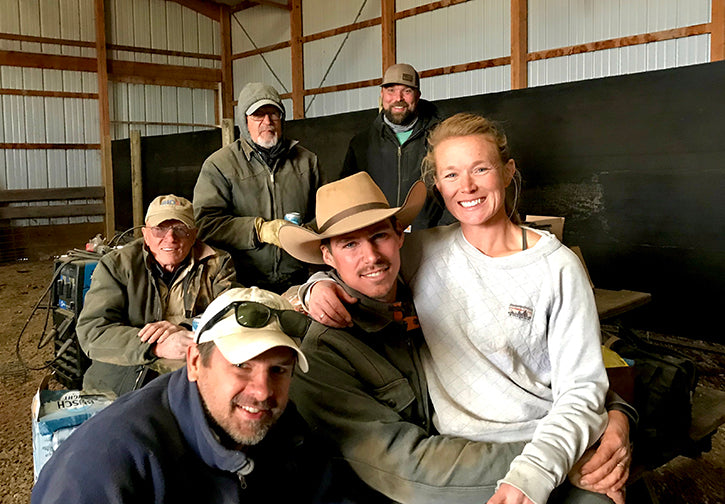 Crew of ranch hands smiling at camera inside barn