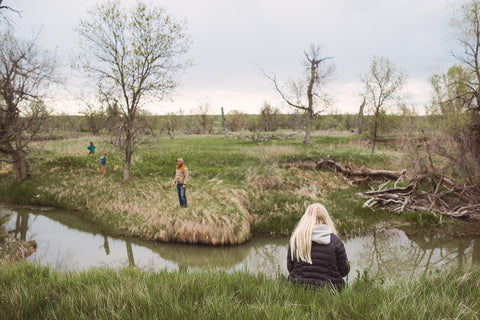 Image of blond girl fishing by a creek with people fishing on the opposite side of the creek