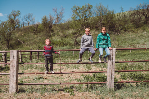 Kids sit on fence at Cheyenne River Buffalo Ranch