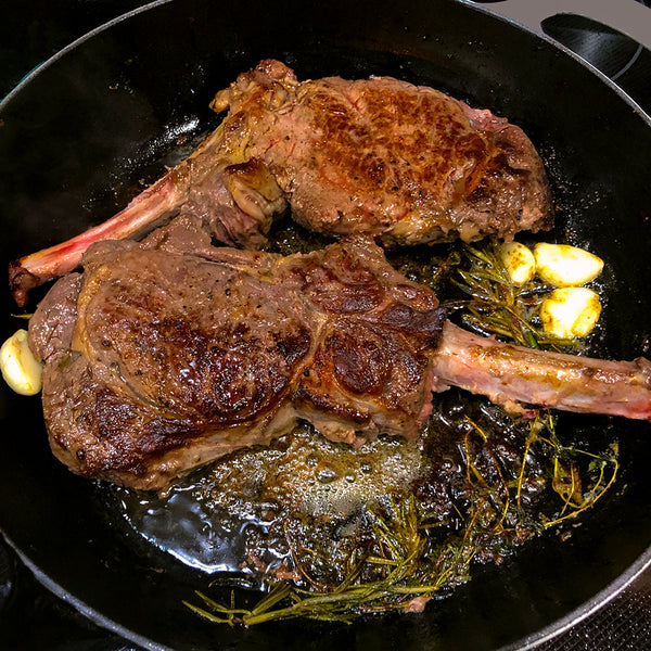 butter-basted bone-in-ribeyes in a black skiller