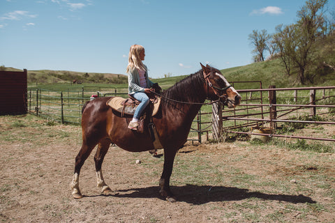 Young girl rides a brown horse at Cheyenne River Buffalo Ranch